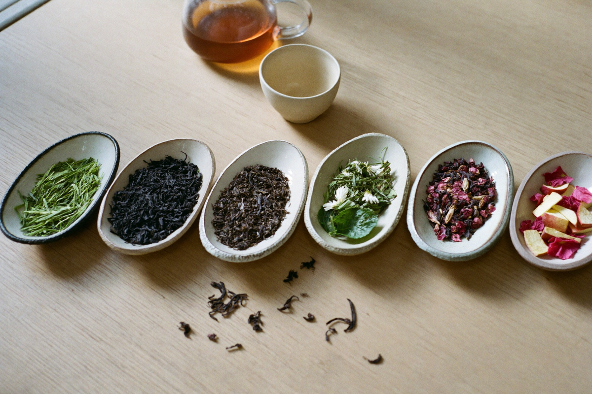 Verschiedene Teesorten in Schalen: grüner Tee, schwarzer Tee, Kräutertee und Früchtetee